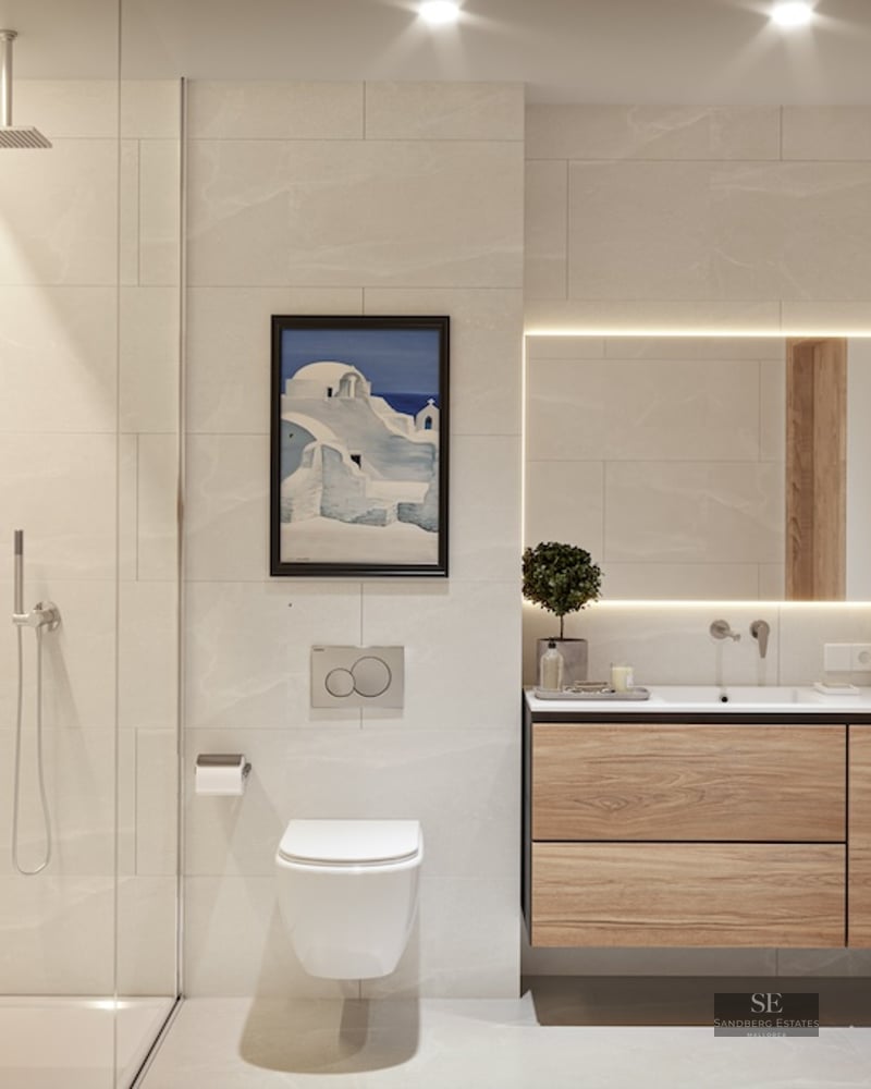 Modern bathroom with beige tiles, floating wood vanity, backlit mirror, and glass walk-in shower.