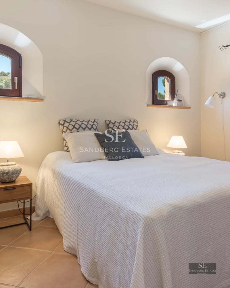 Spacious living room with large windows, natural light and modern furniture. Light wood floors, elegant rug, and fireplace. Garden view.