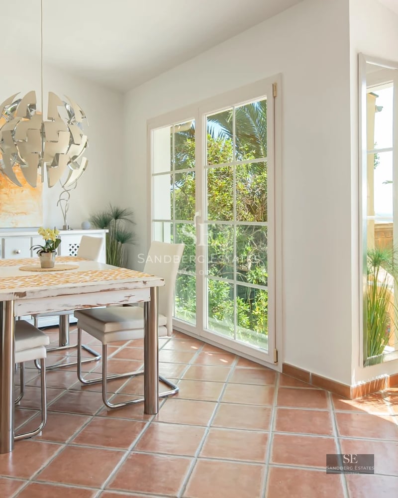 Bright living room with panoramic windows, modern sofas, and access to a balcony overlooking the Mediterranean Sea. Elegant and minimalist design.