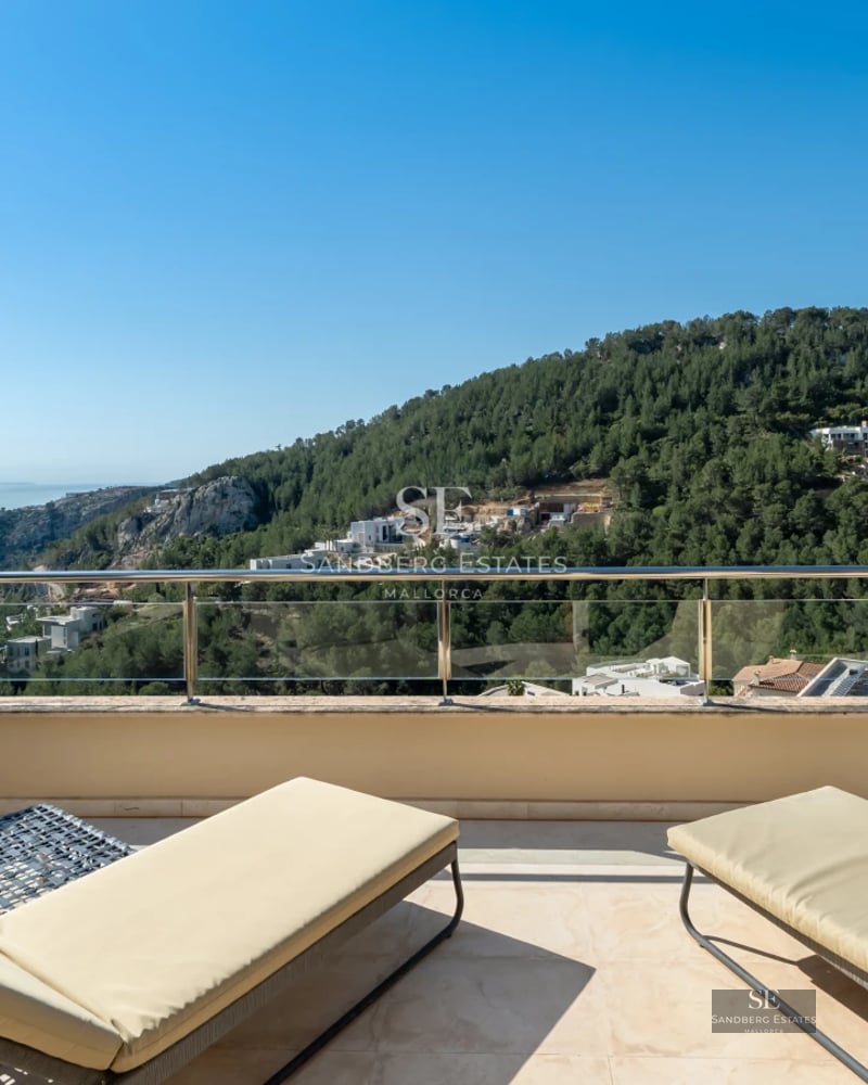 Modern living room with large windows, sea view, and designer furniture. Beige sofa, wood coffee table, and minimalist decoration.