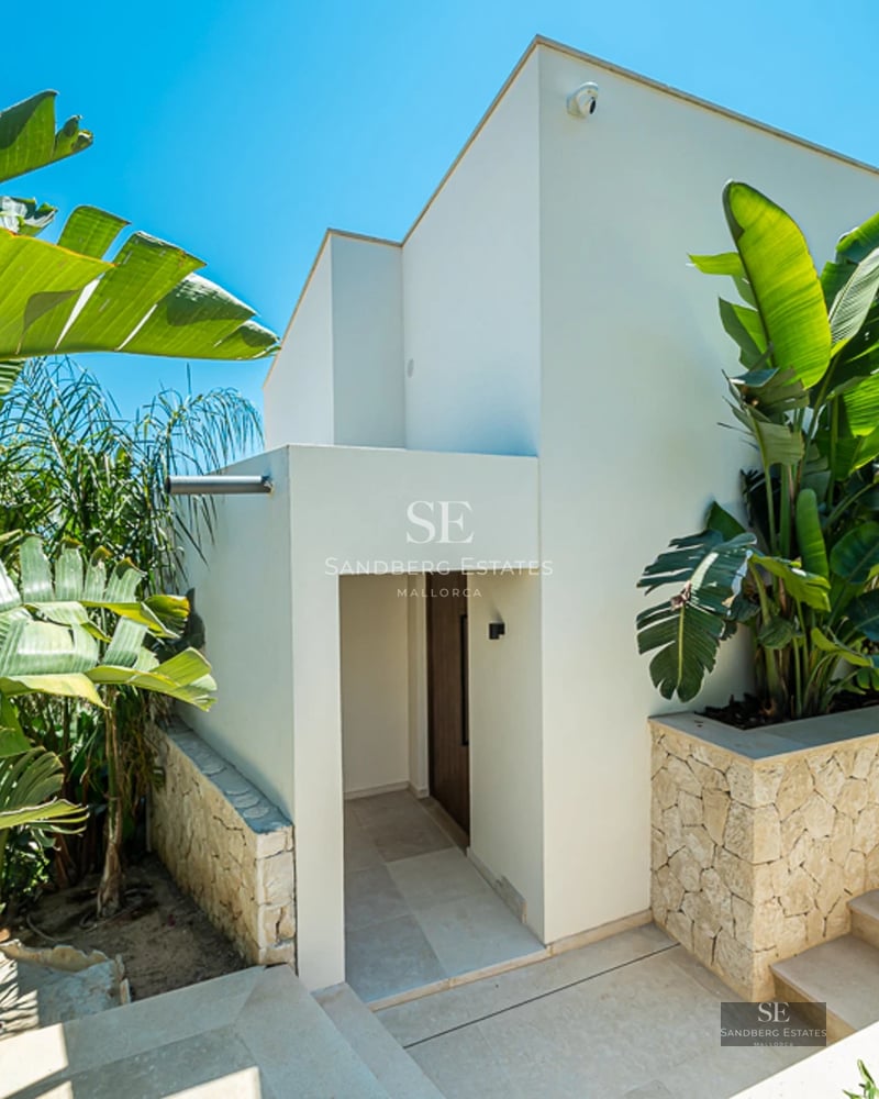 Vue extérieure d'une villa moderne avec piscine à débordement, grandes baies vitrées et jardin luxuriant. Architecture minimaliste et élégante.