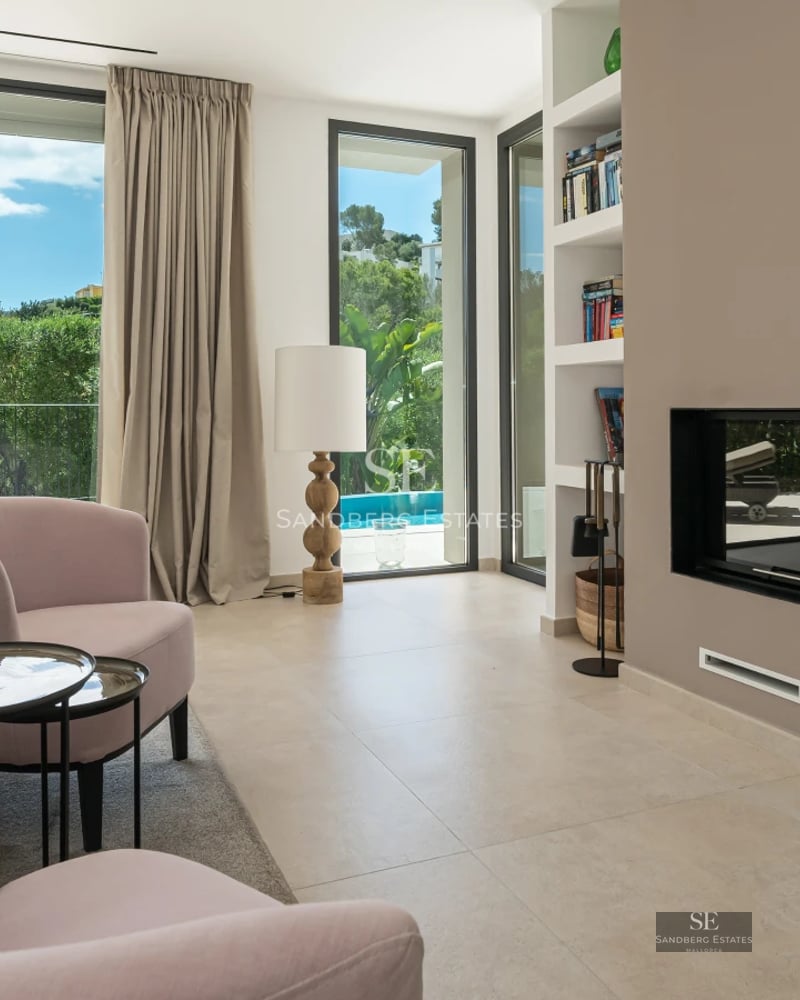 Bright living room with large windows overlooking the sea. Modern interior with beige sofa, coffee table, and stylish decorative details.