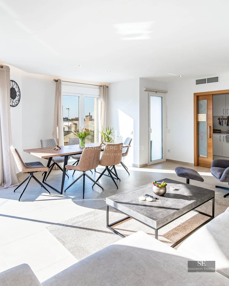 Spacious bright living room with picture windows, modern fireplace, grey sofas, and view of a lush garden with pool. Contemporary design.
