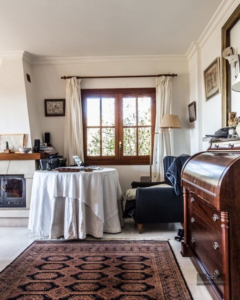 Cozy living room featuring a patterned sofa, a fireplace, an oriental rug, and a vintage wooden secretary desk.