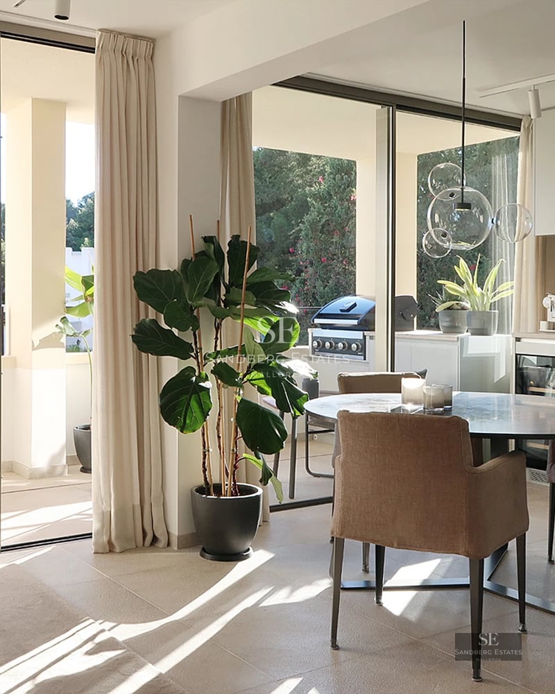 Aerial view of a modern villa with a pool, lush garden, and minimalist architecture. White facade with large windows.