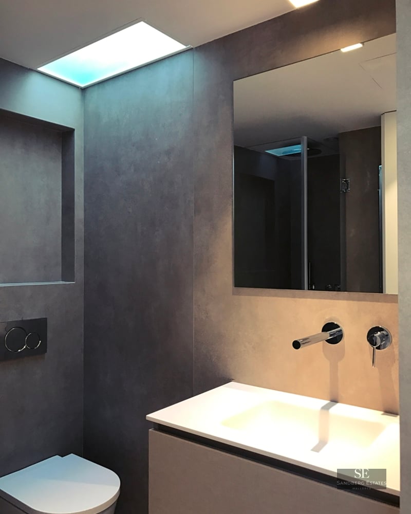 Modern bathroom featuring grey microcement walls, a white floating vanity, chrome faucet, and wall-hung toilet.