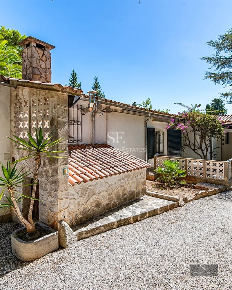Exterior view of a modern villa with infinity pool, manicured garden, and expansive terraces. Minimalist architecture with large windows.
