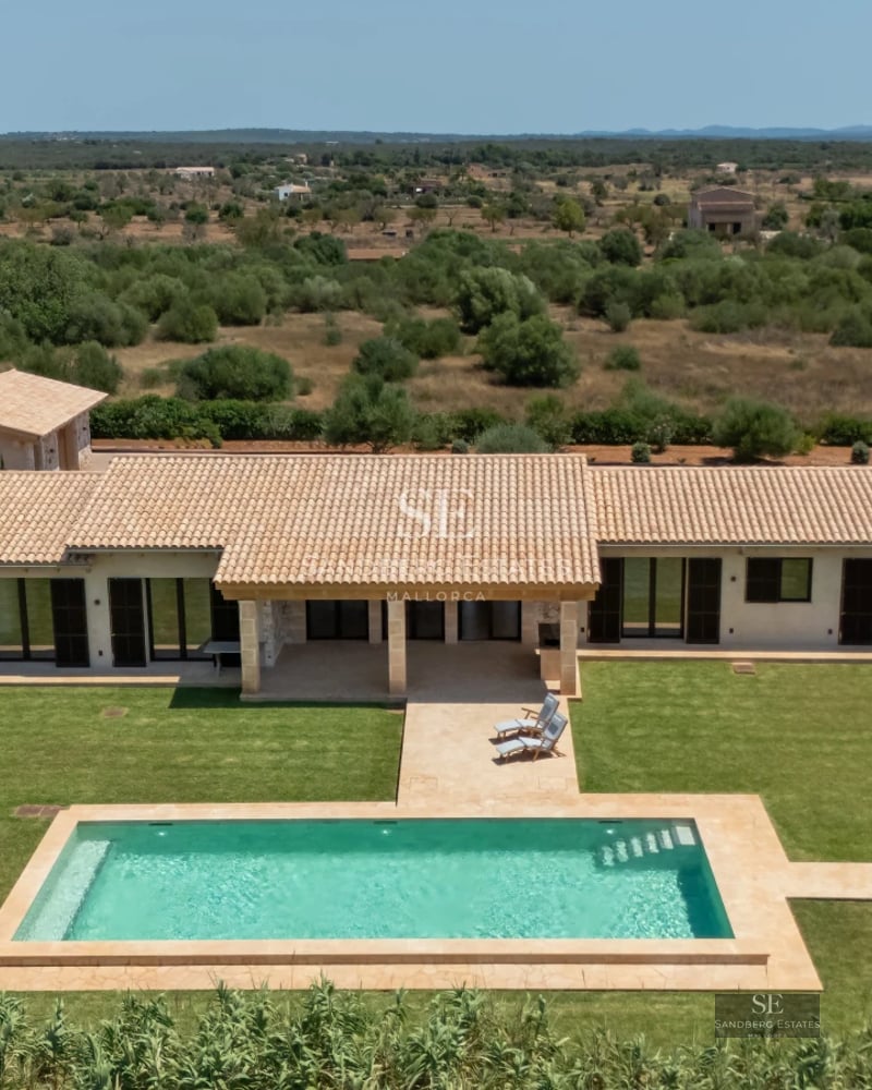 Aerial view of a modern villa with a pool, lush garden, and sleek architectural design. Spacious and bright living spaces.