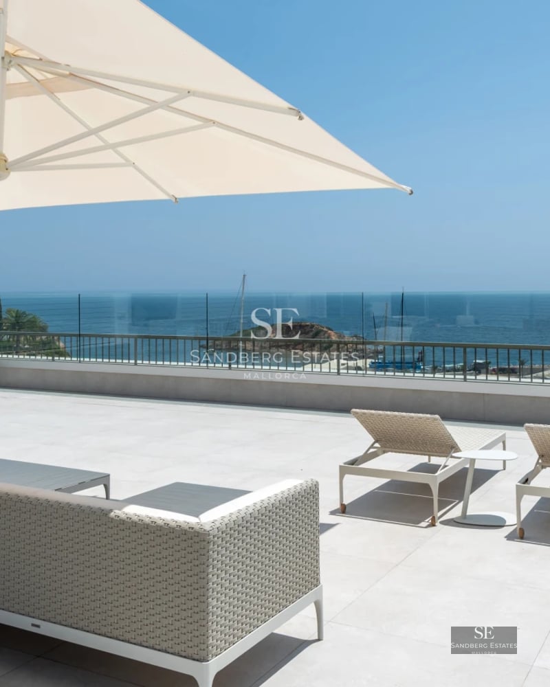 Spacious balcony with panoramic sea view. Modern design, glass railing, soft ambient lighting, and stylish outdoor furniture.
