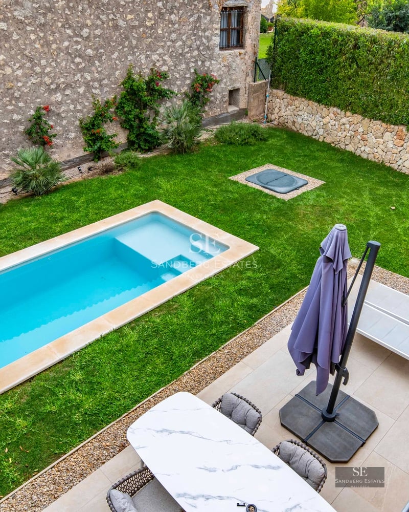 Exterior view of modern villa featuring a swimming pool, lush garden, and expansive windows reflecting sunlight. Avant-garde architectural design.