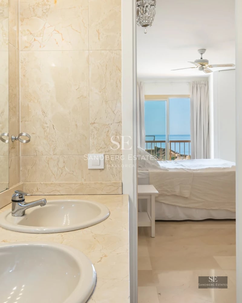 View of an elegant infinity pool merging with the sea horizon. Modern architecture, sun loungers, and lush vegetation.