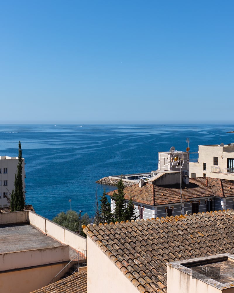 Panoramic view of the blue Mediterranean sea over coastal rooftops under a clear sky.