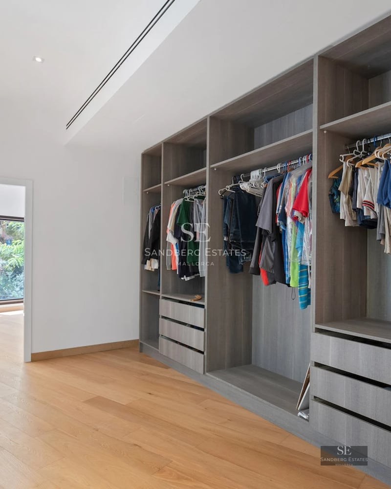 Image of a modern villa with a pool, large windows, and minimalist design. Lush garden and blue skies.