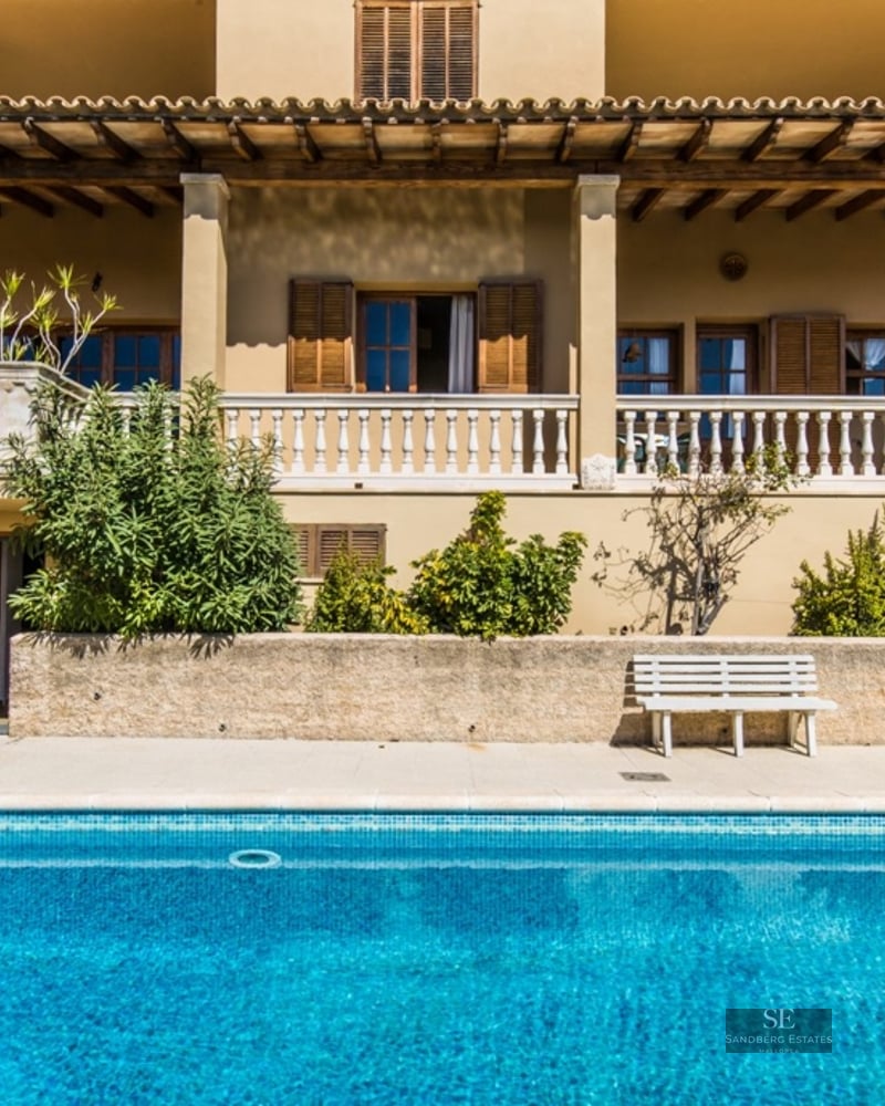 Mediterranean style villa with a large blue swimming pool and a stone balustrade terrace.