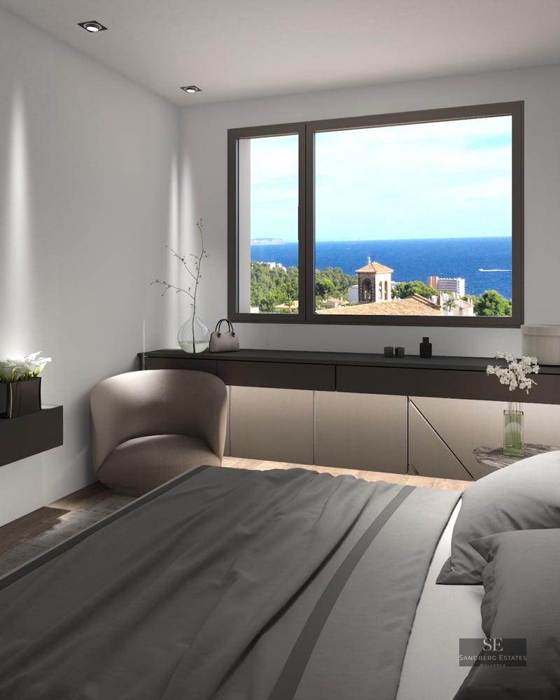Modern bedroom featuring a grey bed, wall-mounted TV, and a window framing a bright blue sea and coastal landscape.