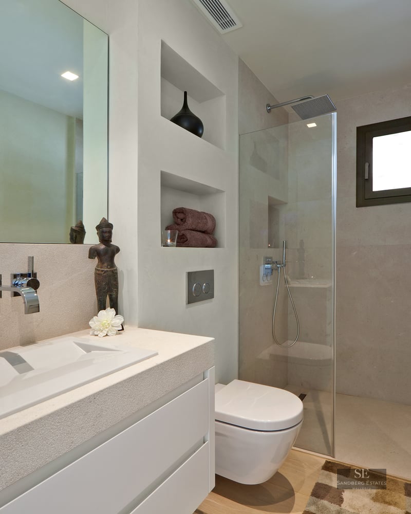 Modern bathroom featuring a stone vanity, wall-mounted toilet, and glass walk-in rain shower.