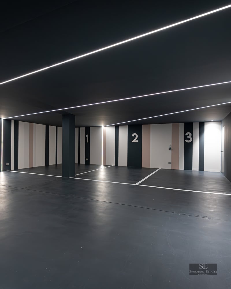 Luxury indoor parking with charcoal walls, numbered spaces 1-3, and linear LED strip lighting on ceiling and walls.
