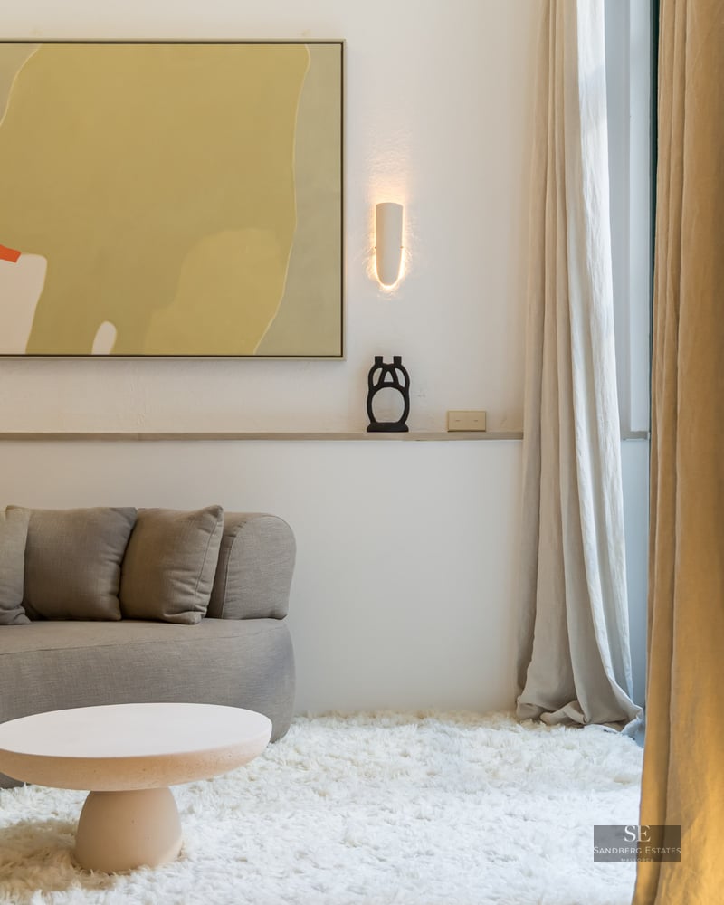 Salon minimaliste avec canapé incurvé gris, tapis shaggy blanc et arches en pierre naturelle.