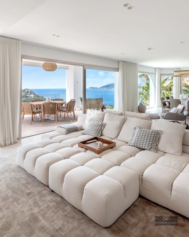Modern balcony with glass railing, light wood flooring, sea view, and minimalist designer furniture. Spacious and bright space.