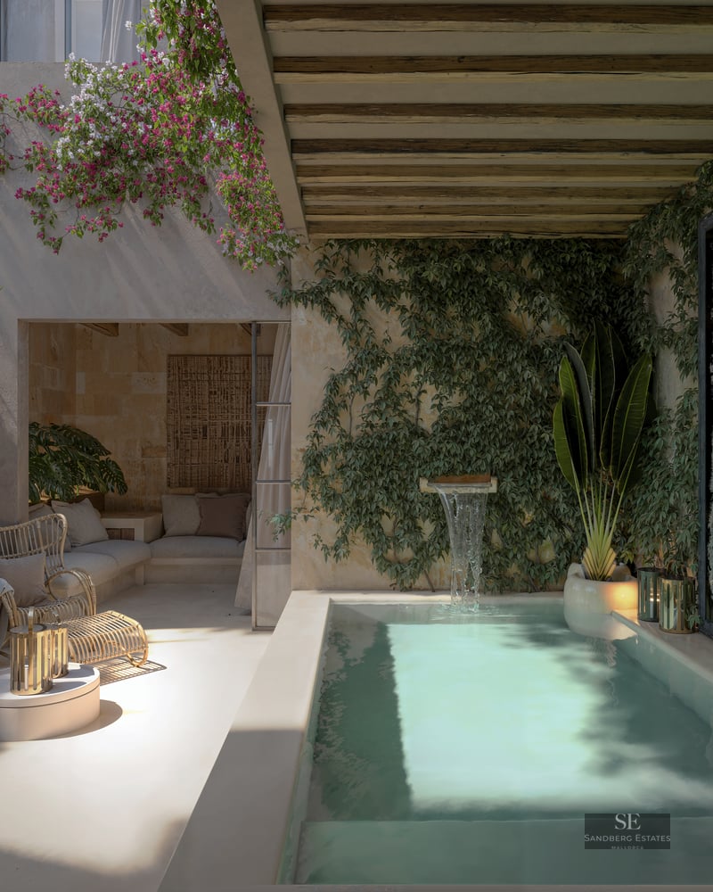 Private plunge pool with waterfall feature surrounded by ivy walls, bougainvillea, and wicker seating under a pergola.