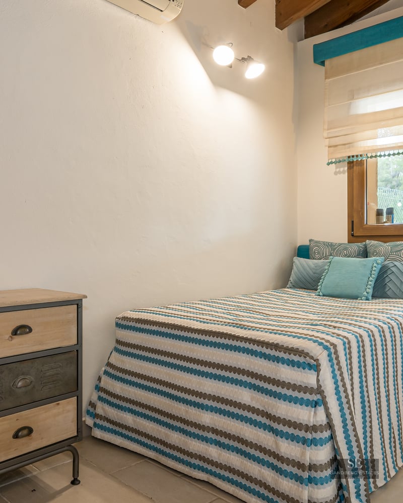 Bedroom featuring a striped bed, teal headboard, wooden furniture, and industrial-style nightstands.