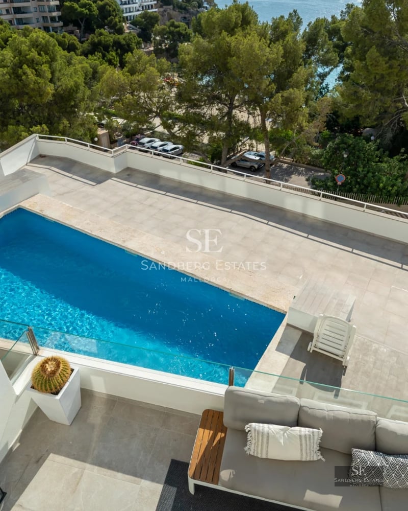 Luxurious living room featuring large windows, showcasing the outdoor pool. Modern design, natural lighting, and high-quality finishes.