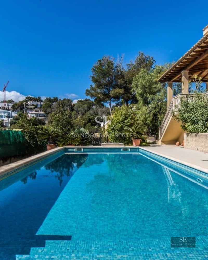 View of a modern villa with infinity pool, manicured garden, and spacious terraces. Sleek and contemporary design.