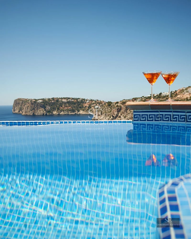 Expansive terrace featuring an infinity pool, ocean views, lounge chairs, and modern design. Minimalist and elegant architecture.