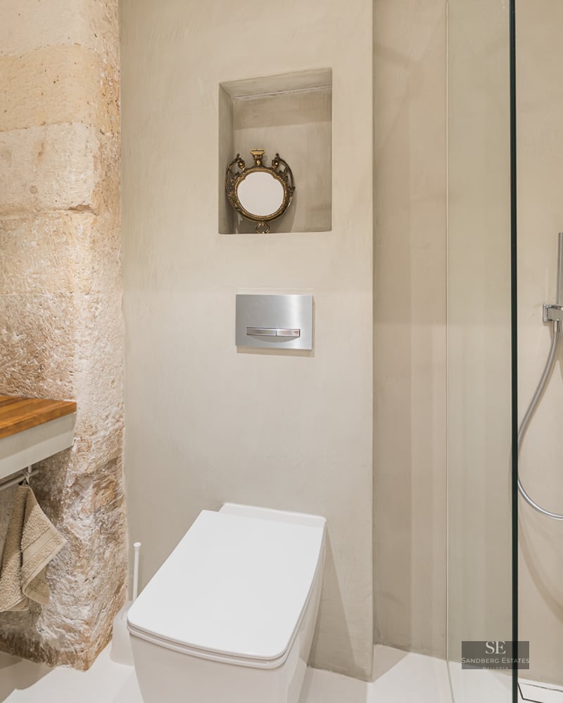 Salle de bain moderne avec lavabo vasque sur plan en bois, pilier en pierre naturelle et douche à l'italienne beige.