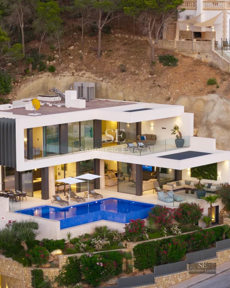 Exterior view of a modern villa with a pool, large windows, and minimalist design. Lush garden.