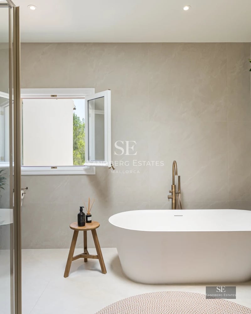 Spacious balcony with sea view. Modern outdoor sofa, wooden floor, glass railing, clear blue sky. Bright and spacious.