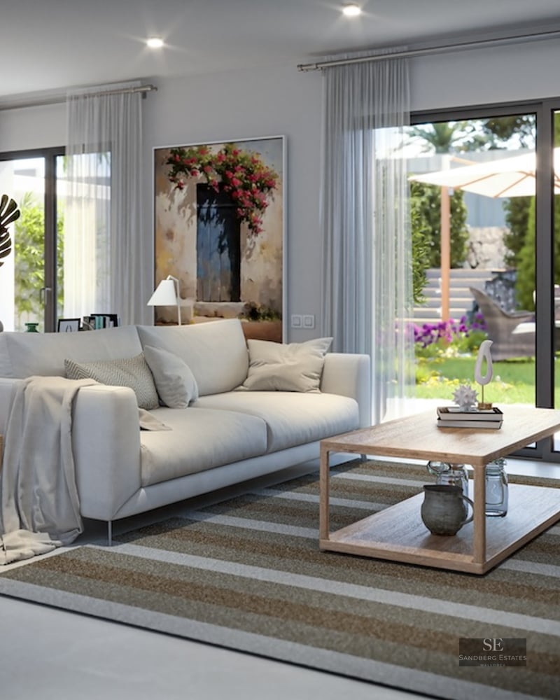 Contemporary living room featuring a white sofa and large sliding glass doors opening to a lush sunlit garden.