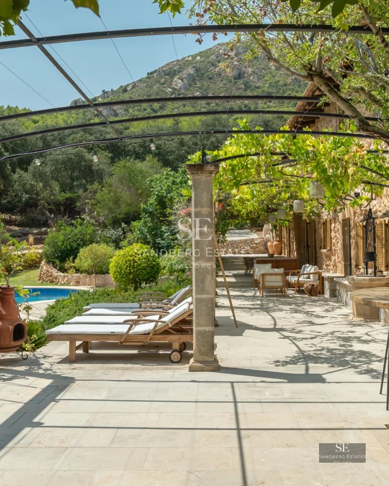 View of pool surrounded by lush greenery, featuring a wooden deck and minimalist modern architecture in the background.