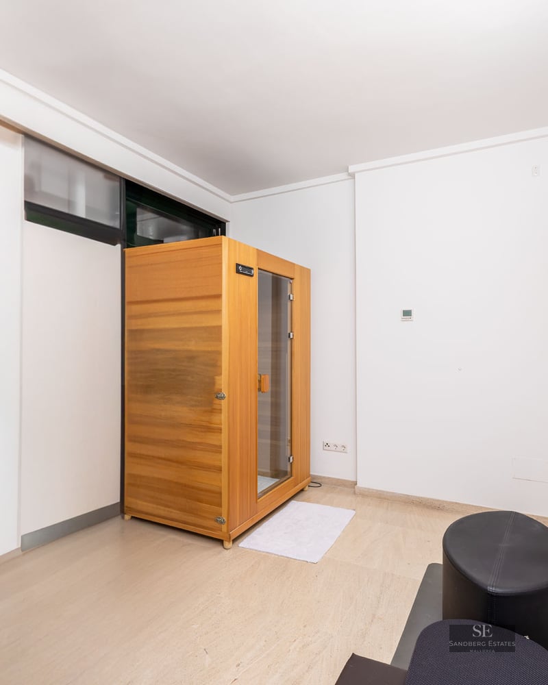 Pièce moderne blanche comprenant une cabine de sauna en bois autoportante et un sol en pierre claire.