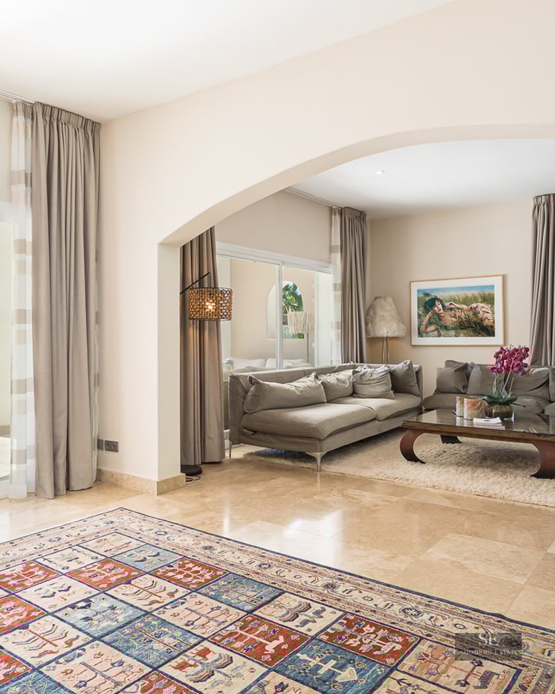 Spacious modern living room with marble floors, gray sofas, and sliding glass doors opening to a blue swimming pool.