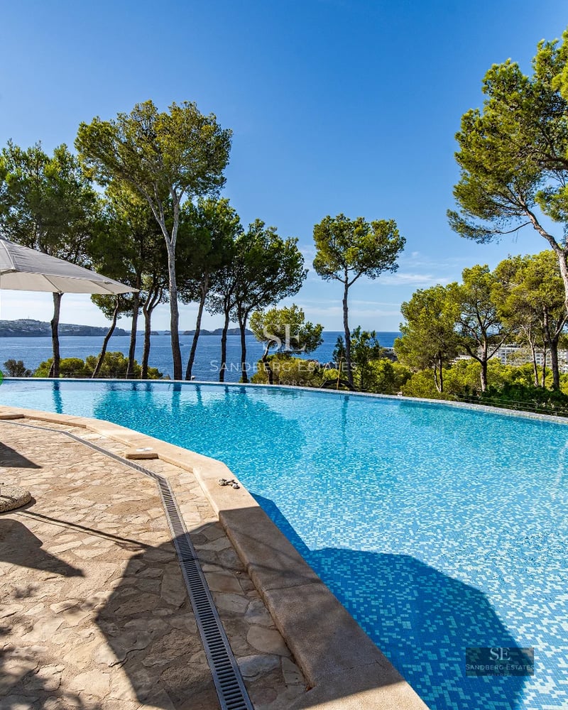Exterior view of a modern villa featuring an infinity pool and spacious terraces. Minimalist architecture and panoramic sea views.