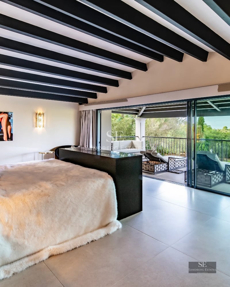 Spacious, bright living room with large windows, modern fireplace, light wood floors, and minimalist decor. Open space with garden views.