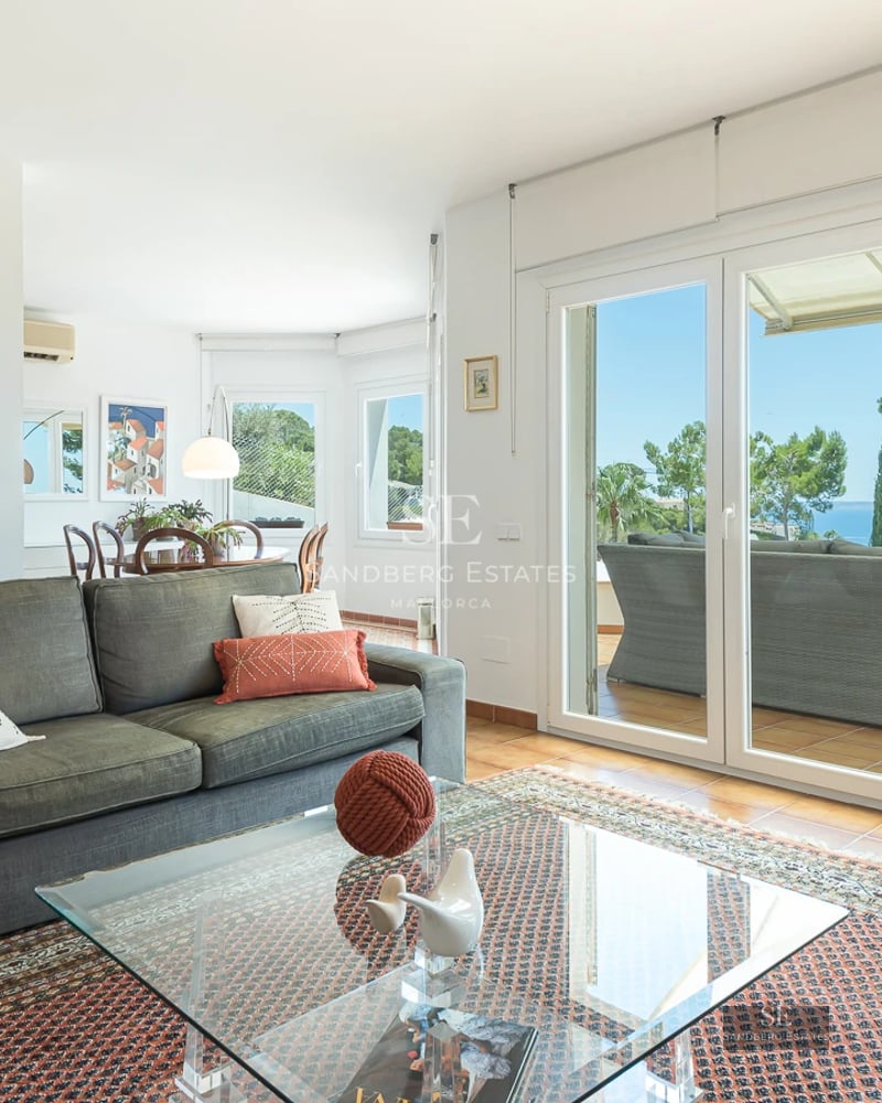 Spacious living room featuring panoramic windows, light wood floors, a modern fireplace, and minimalist designer furniture.