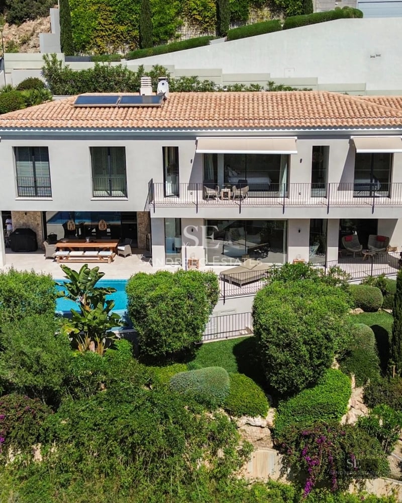 Exterior view of a modern villa with infinity pool. Minimalist design, large windows and lush natural surroundings.