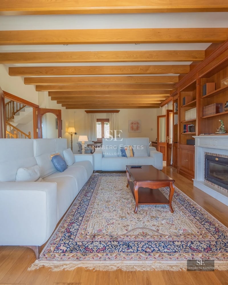 Spacious living room with panoramic sea view windows. Modern design, light wood floors, beige sofas, and blue accents. Abundant natural light.