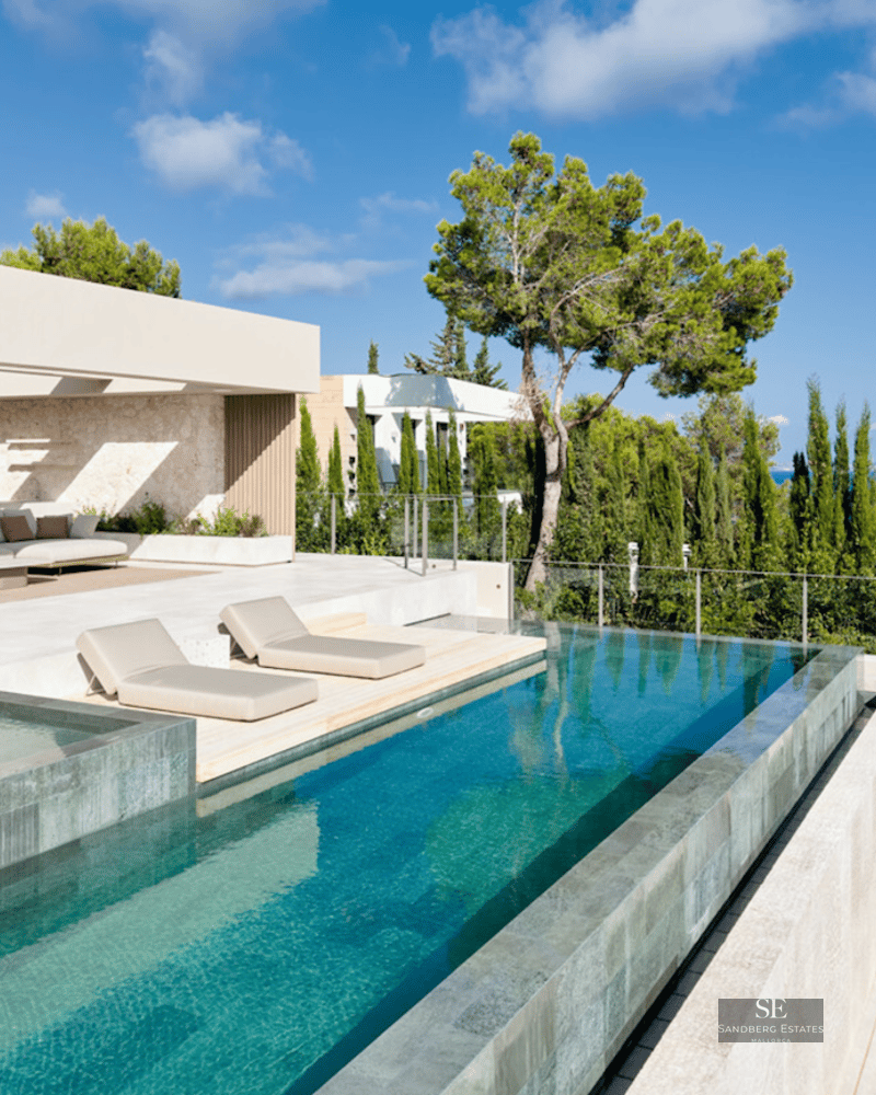 Modern infinity pool with sun loungers overlooking the sea, adjacent to a stylish outdoor lounge and dining area.