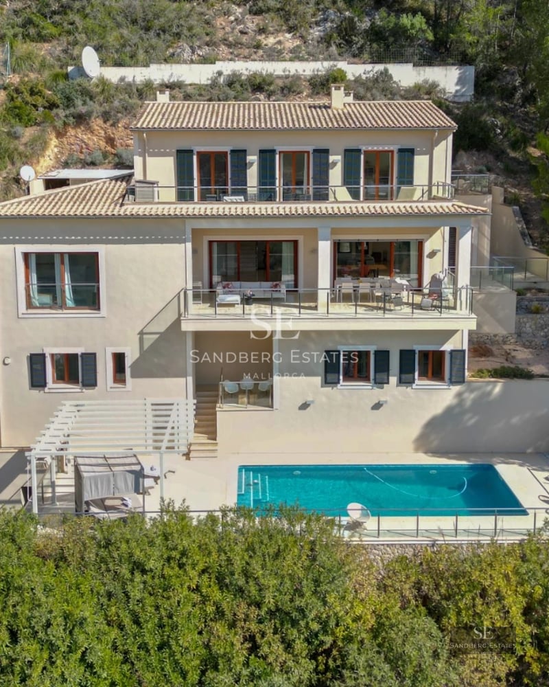 Balcony view with glass railing, wooden floor, lush greenery, and sea view. Modern elegance.