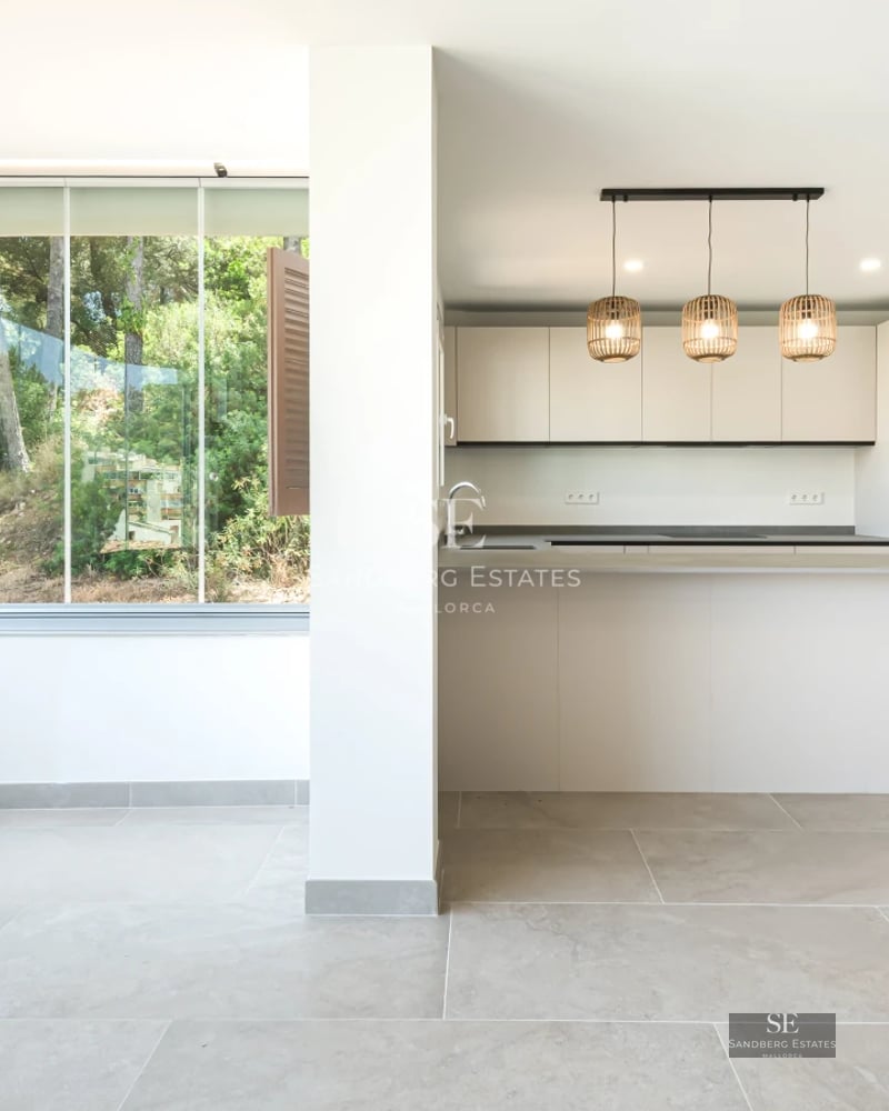 Spacious, bright living room with floor-to-ceiling windows, light wood floors, modern furniture & balcony access with view. Minimalist design.