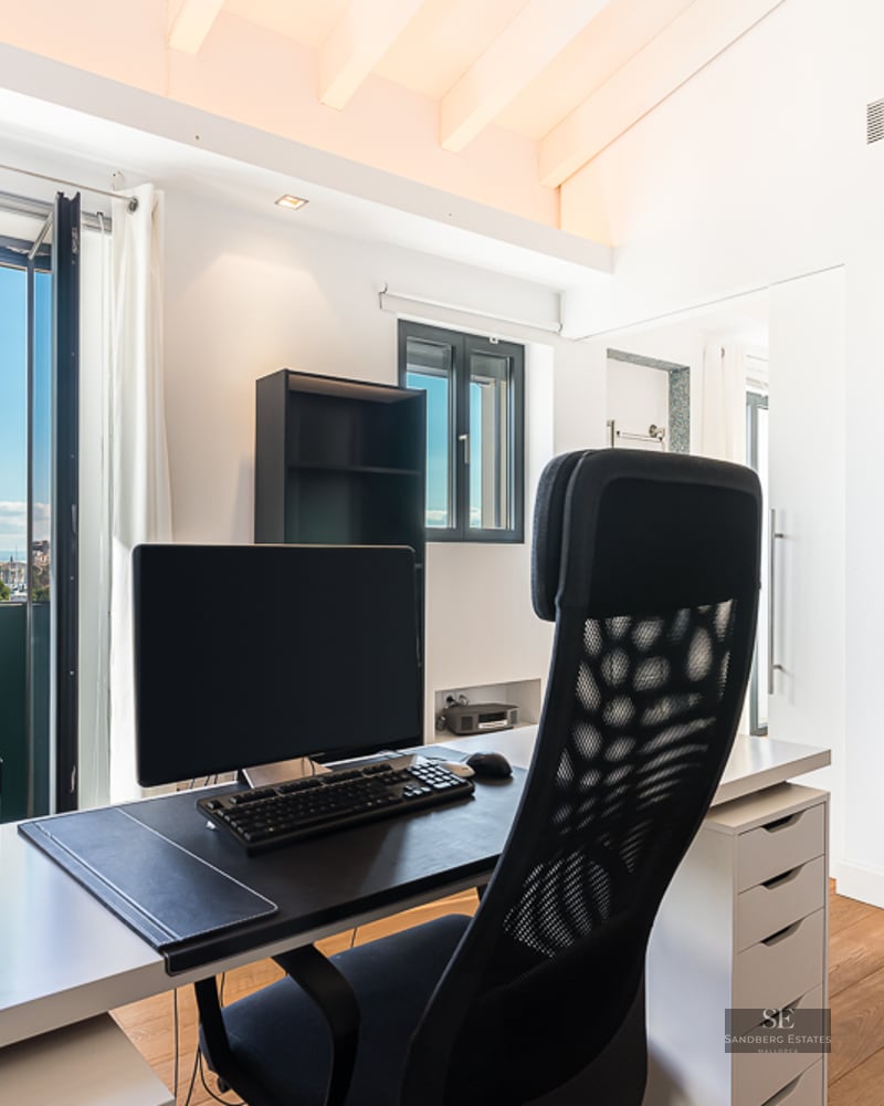 Modern home office featuring a desk, ergonomic chair, and large bookshelf overlooking the Palma Cathedral.