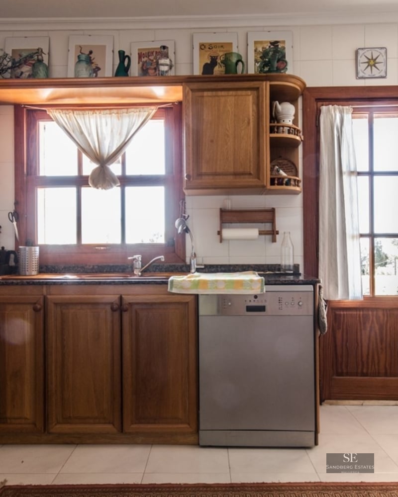 Bright kitchen featuring warm wood cabinets, white tiled walls, granite countertops, and wooden windows.