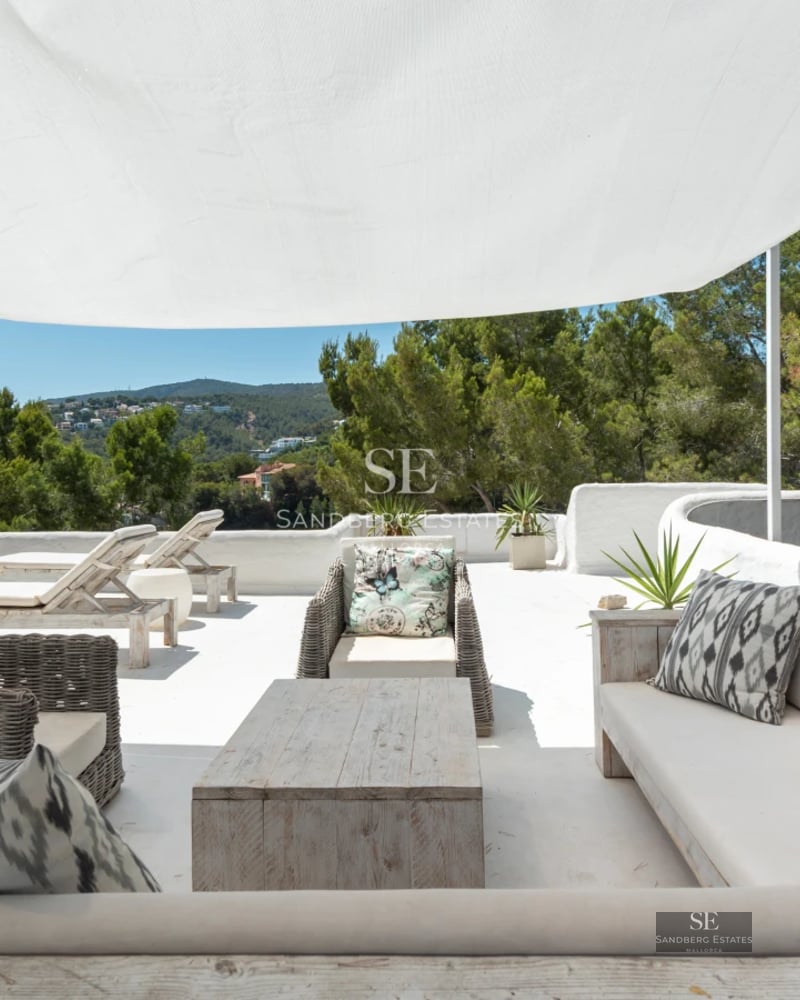 View of infinity pool and garden of a modern villa with lounge chairs and outdoor living area. Minimalist architecture and lush landscaping.