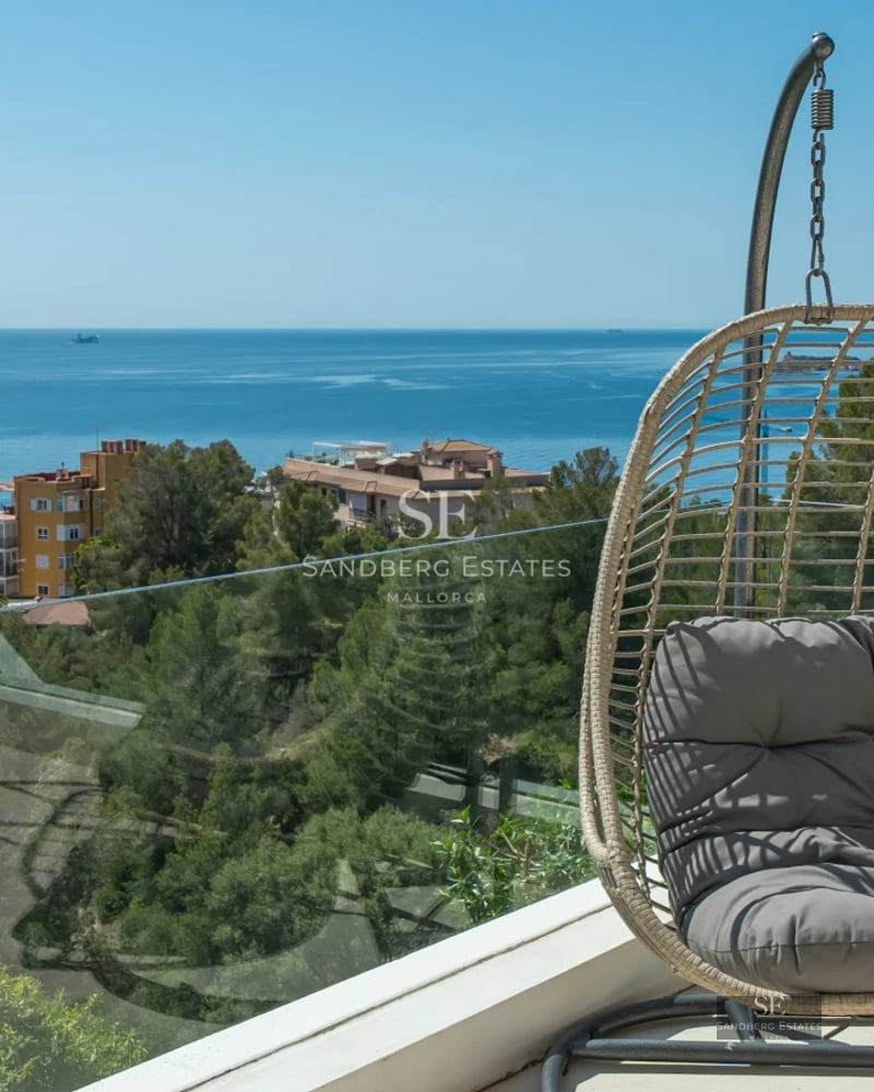 Spacious living room with floor-to-ceiling windows, wood floors, fireplace, and sea view. Modern and elegant furniture. Natural light.