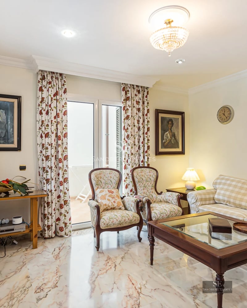 Spacious living room with pool view through large windows. Modern design, natural light, light floors and minimalist furniture.