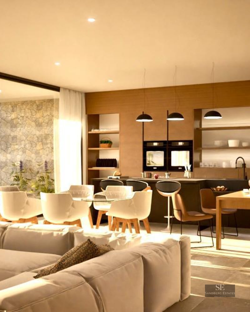 Spacious modern living room with beige sofa, dining area, and large glass doors looking out to a garden.