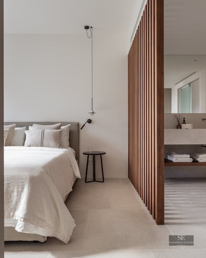 Modern minimalist master bedroom featuring a wooden slat divider and integrated ensuite bathroom with stone vanity.